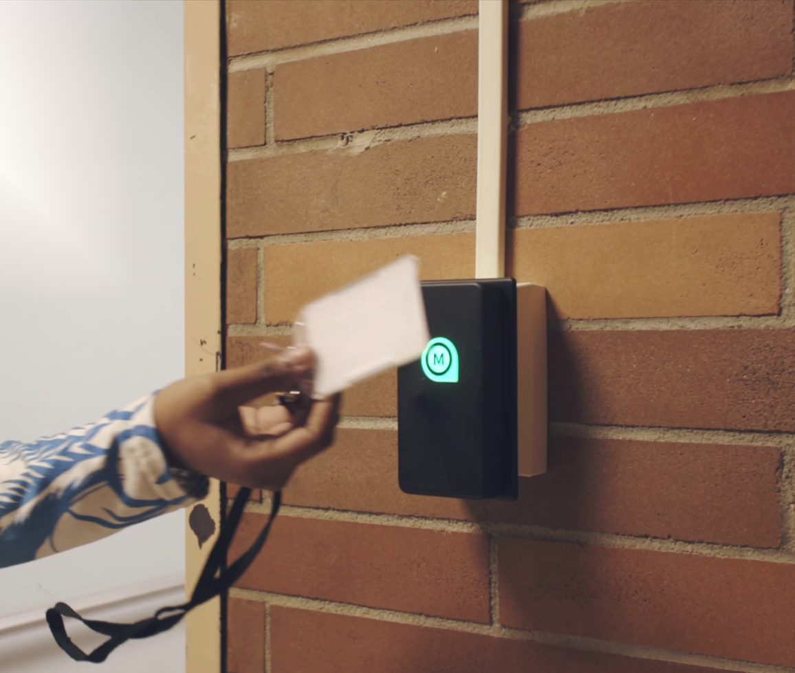 Student tapping an ID card on a MOOV reader by the classroom door